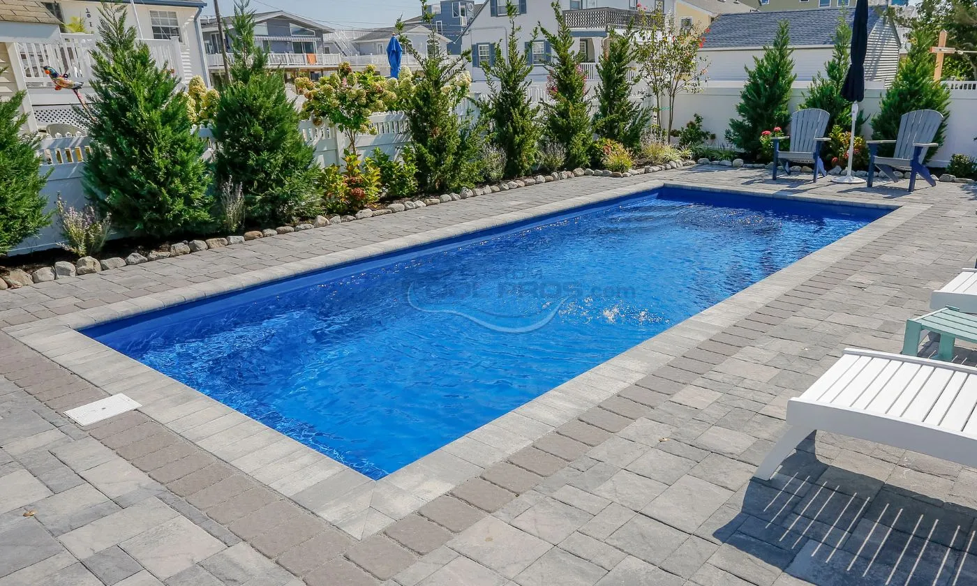 In-ground swimming pool surrounded by landscaped greenery and stone patio, ideal for outdoor relaxation and entertainment.