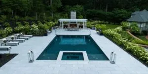 rectangular inground pool with square spa and large pool deck, large grand fireplace with dining sitting area