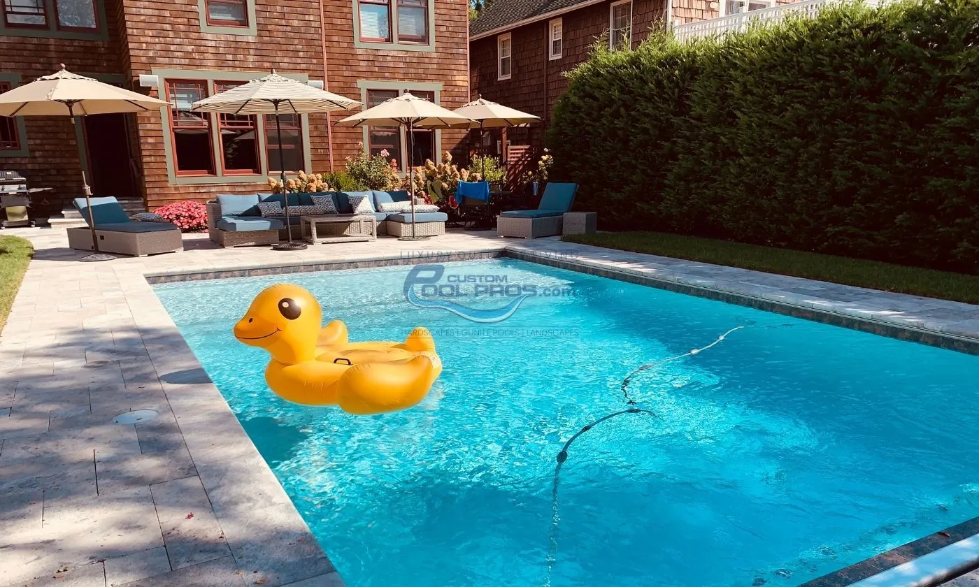 yellow duck floating in an inground swimming pool, pool deck, 4 umbrellas in backyard, pool contractor